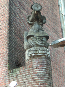 822038 Afbeelding van het door Jo Uiterwaal gemaakte natuurstenen beeld De bakker op de hoek bij de toegangspoort van ...